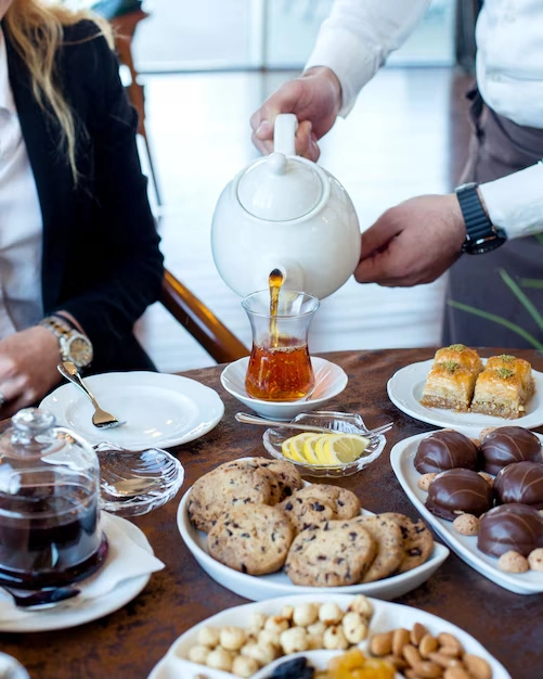 Pouring-tea-with-desserts-and-snacks-on-table